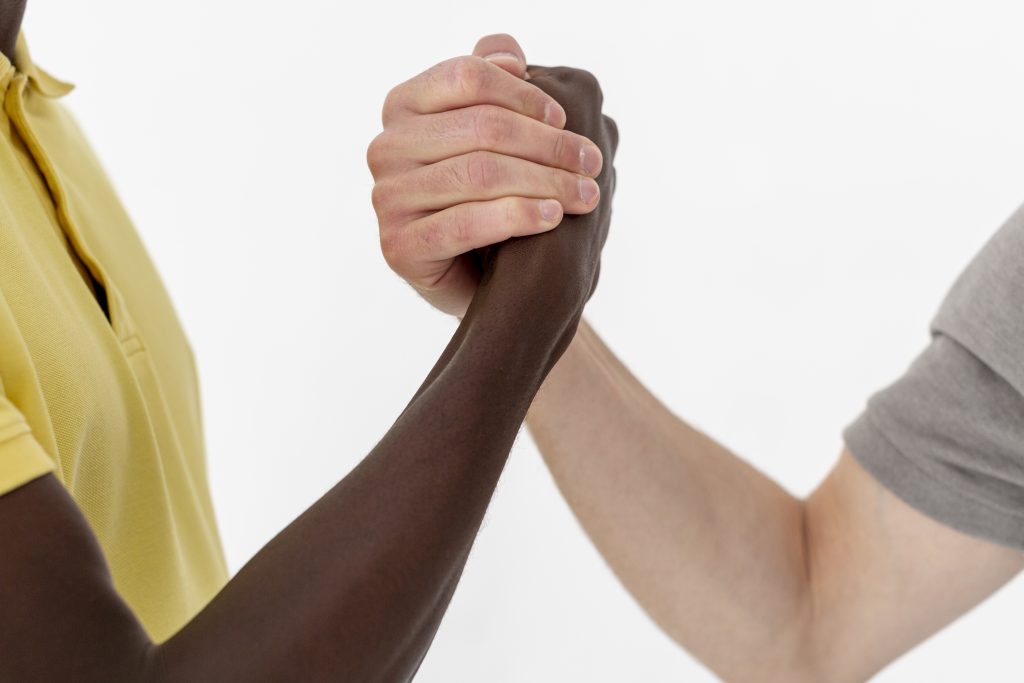 Close-up de um aperto de mãos entre duas pessoas de diferentes tons de pele, simbolizando colaboração, diversidade e parcerias estratégicas no futuro do marketing digital.