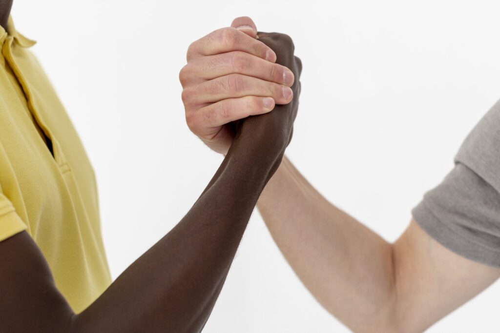 Close-up de um aperto de mãos entre duas pessoas de diferentes tons de pele, simbolizando colaboração, diversidade e parcerias estratégicas no futuro do marketing digital.