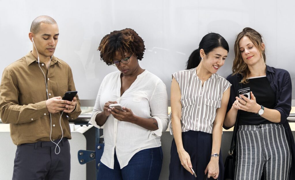 Grupo diverso de pessoas interagindo com seus smartphones, representando diferentes perfis e estilos, destacando a importância de estratégias personalizadas para engajar públicos variados.