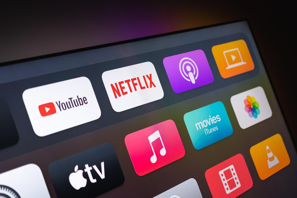 Tela de uma smart TV exibindo aplicativos de streaming, como YouTube, Netflix, Apple TV e iTunes, representando a evolução do consumo de mídia digital.